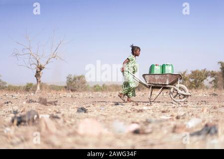 Little African Woman Transporting Fresh Water as a drought symbol Stock Photo