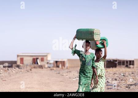 Working African Ethnicity Schoolgirl Collecting Fresh Water for lack of water symbol Stock Photo