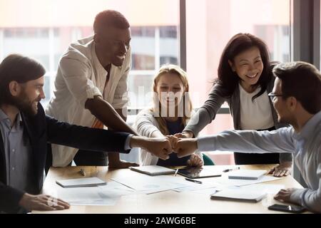 Happy diverse employees team joining fists, celebrating success Stock Photo