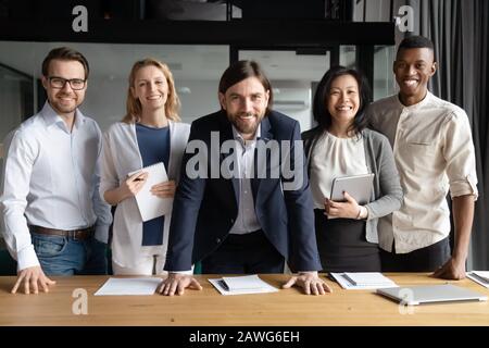Smiling diverse business people with team leader looking at camera Stock Photo