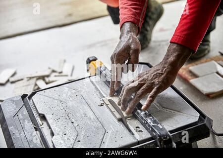 Close up of a man's hands using a tile saw to cut ceramic tile Stock Photo