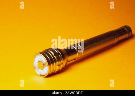 Metal flashlight on a yellow background Stock Photo