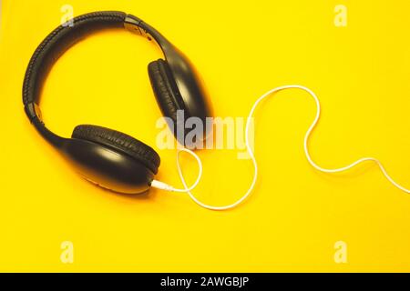 Headphones with white cable on a yellow background. black earphones Stock Photo