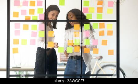Two multiethnic affiliates create ideas writing it on sticky notes Stock Photo