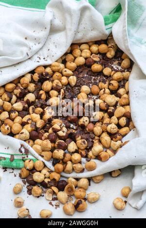 Corylus avellana. Cleaning off skins of roasted hazelnuts in a towel. Making homemade vegan hazelnut chocolate spread Stock Photo