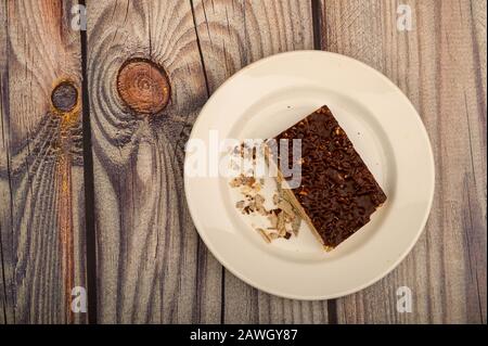 A piece of waffle cake on a white plate on a wooden background. Close up Stock Photo