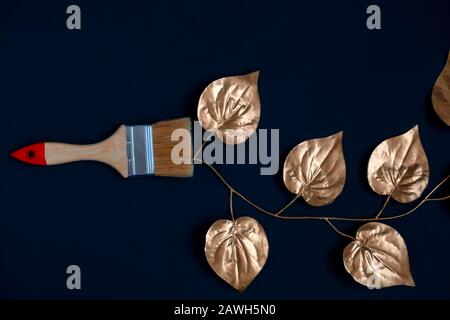 top view paint brush with golden ive leaves on a black background Stock Photo