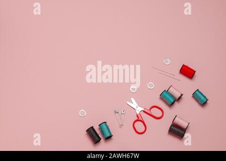 top view flat lay red ,pink and and blue sewing or embroidery supplies on a soft pink background with space for text Stock Photo