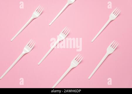 top view white plastic forks pattern on a pastel pink background Stock Photo