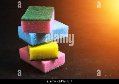 Foam sponge for washing dishes on a dark background with a Sunny dawn Stock Photo