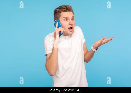 Why? How could you? Displeased angry man in t-shirt calling partner, having problems in negotiations, unpleasant talk on cellphone, shocked by bad new Stock Photo