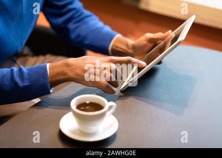 Black man sitting in coffee shop drinking cup of coffee Stock Photo