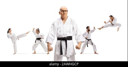 Elderly karate master with black belt posing with people exercising behind isolated on white background Stock Photo