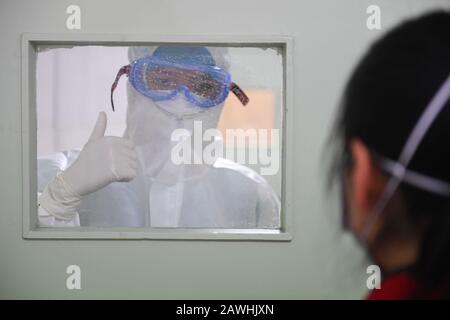 (200209) -- CHANGSHA, Feb. 9, 2020 (Xinhua) -- Yi Junfeng (L) gives a supportive thumb-up to a quarantined patient at a fever clinic of Hunan People's Hospital in Changsha, central China's Hunan Province, Feb. 7, 2020. Amid the current novel coronavirus outbreak, 22-year-old male nurse Yi Junfeng has volunteered to join the battle against the epidemic. After a series of professional trainings, he now works as a front-line fever clinic nurse at Hunan People's Hospital in Changsha. Yi believes that a male nurse has comparative advantages in terms of physical strength and etc, and can play an imp Stock Photo