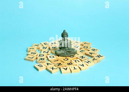 Mind concept. A meditating figure sits on a pile of different letters. The concept of thinking, mind, development and creativity. Stock Photo