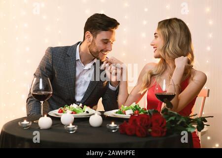 Romantic Beautiful Couple Dining In Restaurant, Loving Man Kissing Girlfriend's Hand Stock Photo