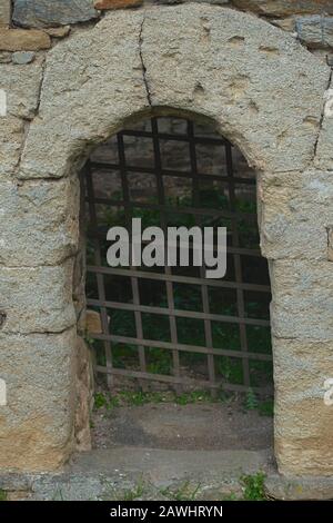 Stone archway and rustic metal gate representing dungeon entrance Stock Photo