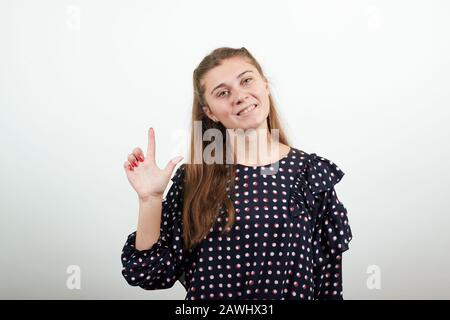 Fair-haired girl in a black dress woman has an idea and raises index finger Stock Photo