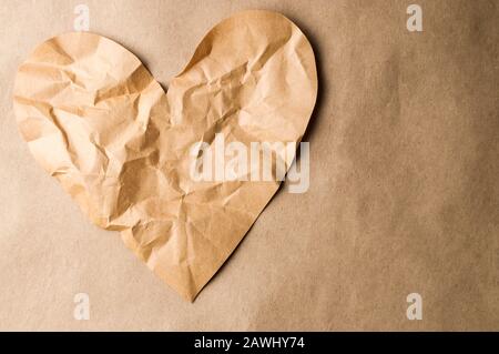 Crumpled brown paper heart that could either be recycled or damaged goods, depending on your perspective Stock Photo