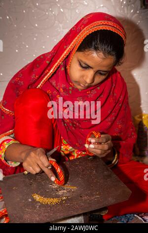 India, Rajasthan, Shekhawati, Nawalgarh, making traditional lac bangles by hand, young woman pressing cheap jewel decoration into hot bangle Stock Photo