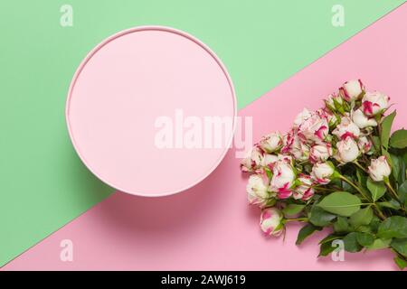 Pink round gift box, bouquet of small roses on pastel two-color background pink and green, copy space, flat lay. March 8, February 14, St. Valentine's Stock Photo