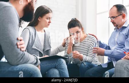 Understanding people calming crying woman during group session meeting in rehab Stock Photo