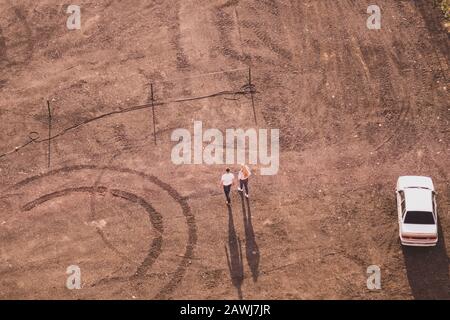 Couple walking on the sand near a car. aerial view. ground with tracks and footprints. view from above of a couple of tourists. conceptual background Stock Photo