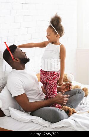 Father and daughter wearing crowns, playing in bedroom Stock Photo