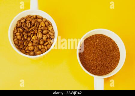 Whole coffee beans and ground coffee in cups on yellow background Stock Photo