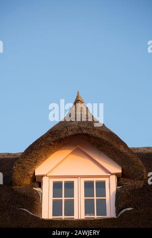 A thatched house at sunrise in February on the seafront of Lyme Regis. The area is popular with fossil hunters and many people come to visit the famou Stock Photo