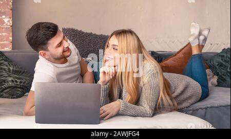 Young just married couple lying on bed at home and using laptop Stock Photo