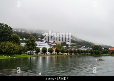 Editorial 09.04.2019 Bergen Norway View of the central park with lake in the city with fog covering the homes on the hillside of Floyfjellet mountain Stock Photo