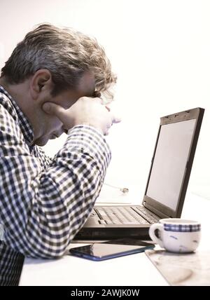 Remote IT support. Tired man works at home Stock Photo