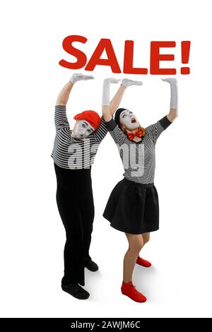 Two mimes posing on white background. Man and woman holding heavy lettering SALE Stock Photo