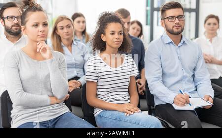 Business conference concept. Young people sitting together on conference and listenning. Multiethnic community. Stock Photo