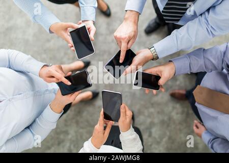 Group of young hipsters holding phone in hands. Friends having fun together with smartphones. Stock Photo