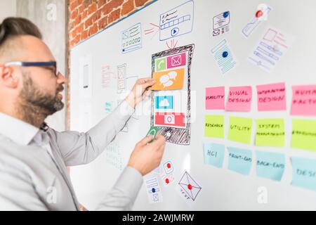 Designer man drawing website ux app development and holding smart phone on hand. User experience concept. Stock Photo