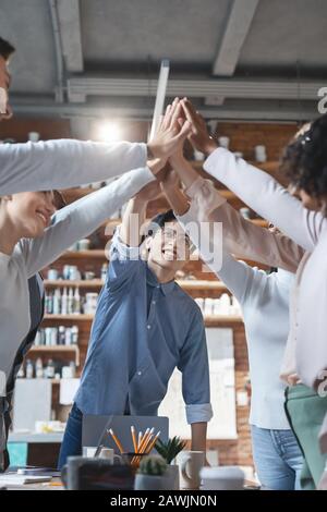 Inspired manager giving high five to his international young team Stock Photo