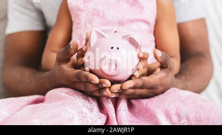 Black father and daughter holding piggy bank, close up Stock Photo