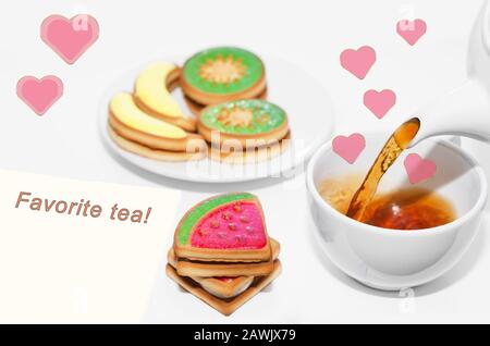 Tea is poured from a teapot, Fruit cookies and pink hearts on a white background. Stock Photo