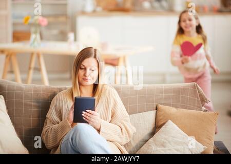 Blurred portrait of cute little girl running up to busy mother on Mothers day, copy space Stock Photo