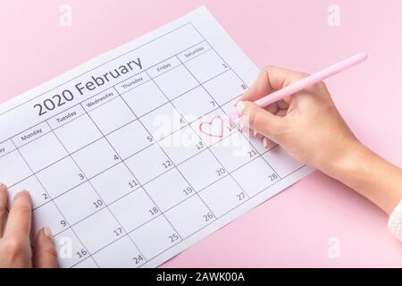 Saint Valentine Day in heart shape circle, woman drawing in calendar Stock Photo