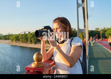 Mature woman photographer with camera taking photo picture Stock Photo