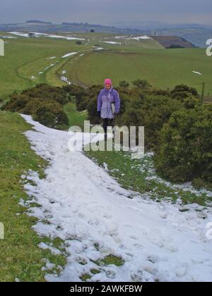 Woman walking Offas Dyke long distance footpath in the snow during winter near Knighton Powys Wales Stock Photo