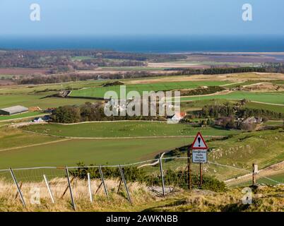 Agricultural landscape view to Belhaven Bay with dangerous cliff warning triangle sign from Traprain Law hill, East Lothian, Scotland, UK Stock Photo