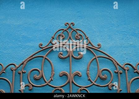 A Decorative Piece of Wrought Iron Mounted to a Bright Colored Stucco Wall Stock Photo