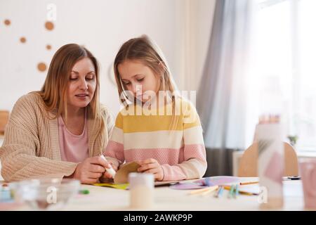 Warm-toned portrait of mature mother enjoying art and crafts with cute daughter in home interior, copy space Stock Photo