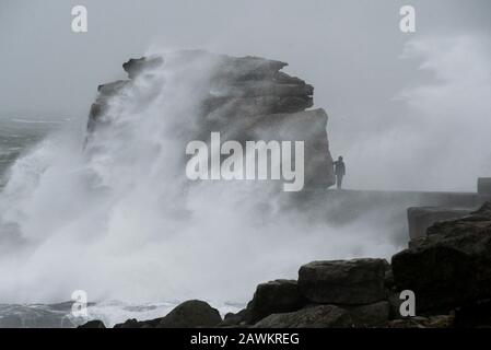 Portland Bill, Dorset, UK.  9th February 2020. UK Weather.  A thrill seeker risks his life by walking onto Pulpit Rock at Portland Bill in Dorset and risks being swept in to the sea as huge waves from Storm Ciara crash against the limestone pillar.  Picture Credit: Graham Hunt/Alamy Live News