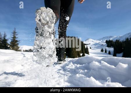 Close-up shoes of trail runner woman running in winter mountains trail on snow.  Stock Photo