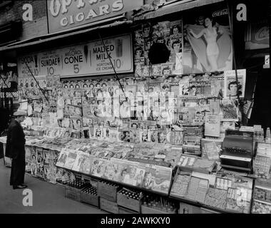 Newsstand, 32nd Street and Third Avenue, Manhattan. Newstand next to State Coffee Shoppe, large display of magazines, ads for sundaes, Coca-Cola above, boxes of sodas below, man at left Stock Photo